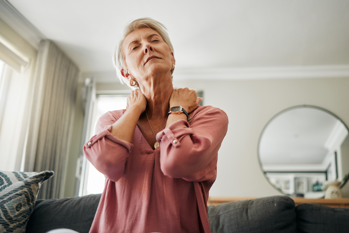 Senior woman, neck pain and stress in living room home of spine injury, fibromyalgia and osteoporosis. Sick, tired and fatigue lady in orthopedic, arthritis and health problem stretching body muscle